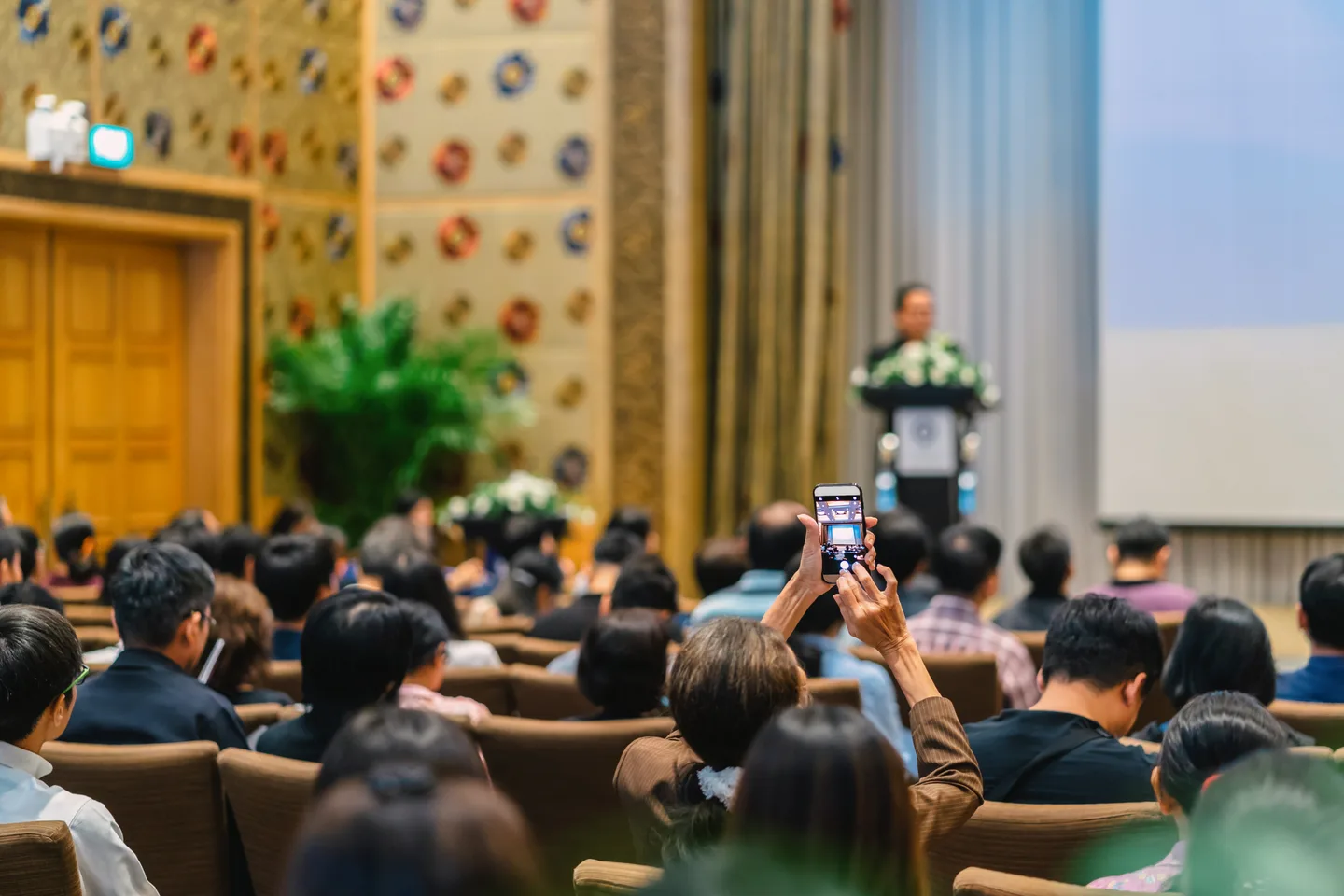 Audience members listening to a presentation in a conference hall