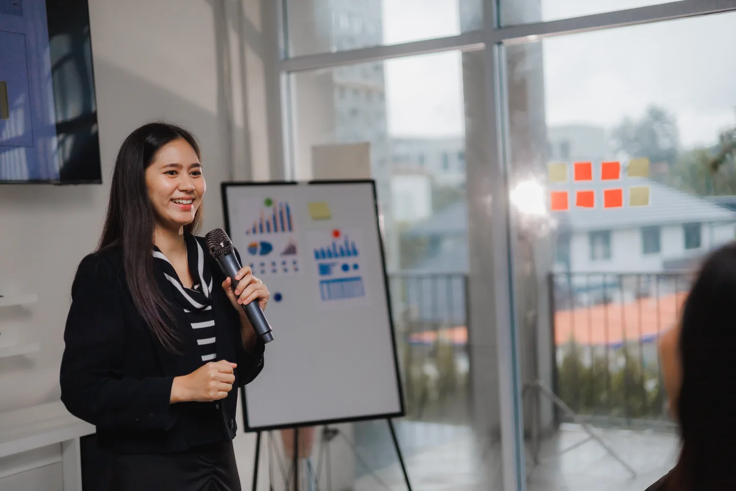 A woman presenting business information beside charts